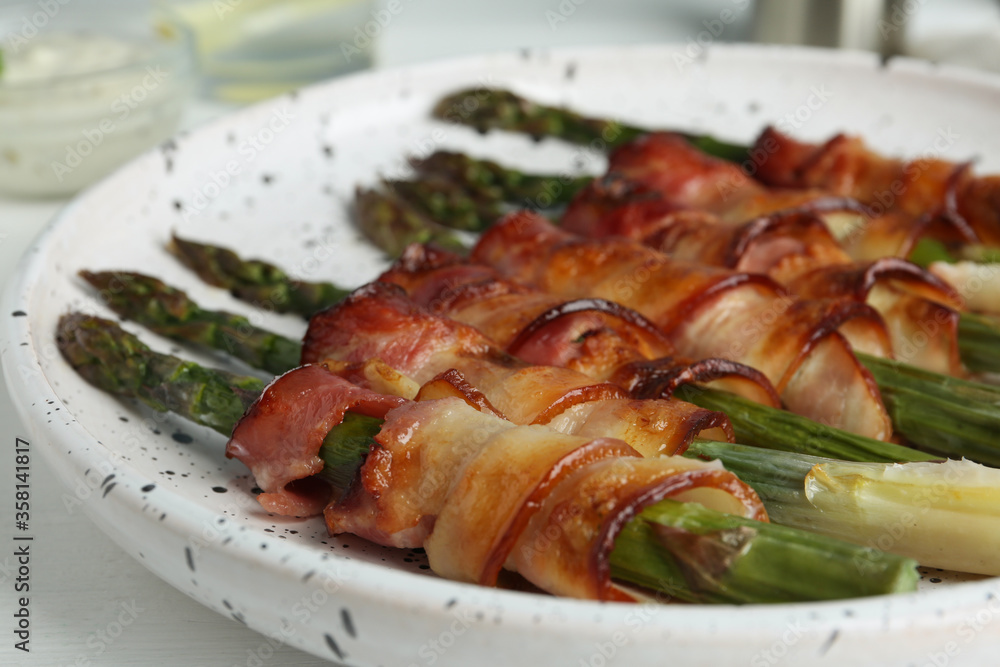 Oven baked asparagus wrapped with bacon on plate, closeup Oven baked asparagus wrapped with bacon on plate, closeup
