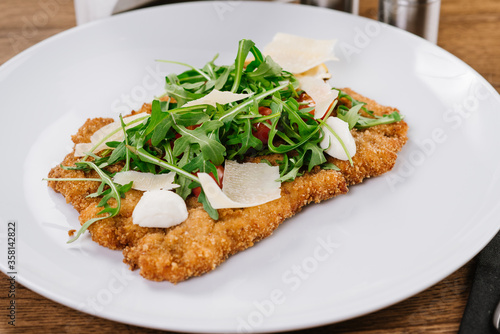 A dish of chop meat with arugula and cheese on wooden background