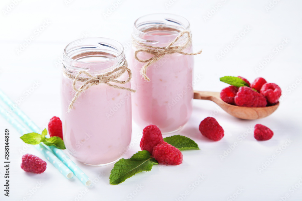 Raspberry smoothie in glass jars with spoon on white wooden table Raspberry smoothie in glass jars with spoon on white wooden table