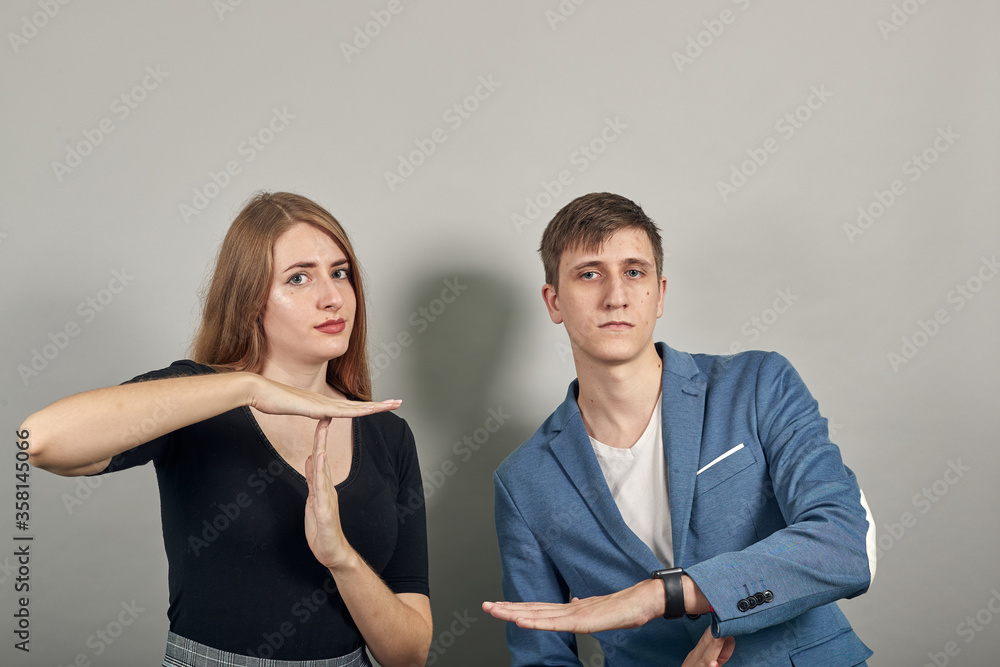 Time out gesture, break, doing t symbol or sign with help of hands. Young attractive couple boyfriend girlfriend two people, dressed black t-shirt, blue jacket, grey background Time out gesture, break, doing t symbol or sign with help of hands. Young attractive couple boyfriend girlfriend two people, dressed black t-shirt, blue jacket, grey background