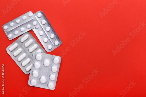 White pills in blisters on red background © 5second