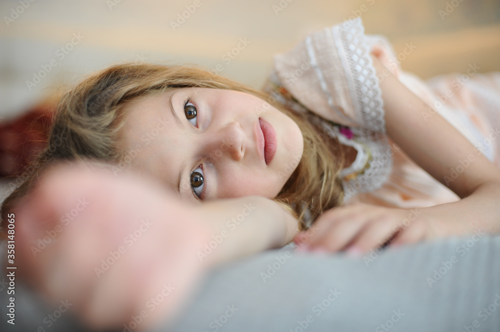 beautiful caucasian little girl lying on bed indoors home room relaxing ...