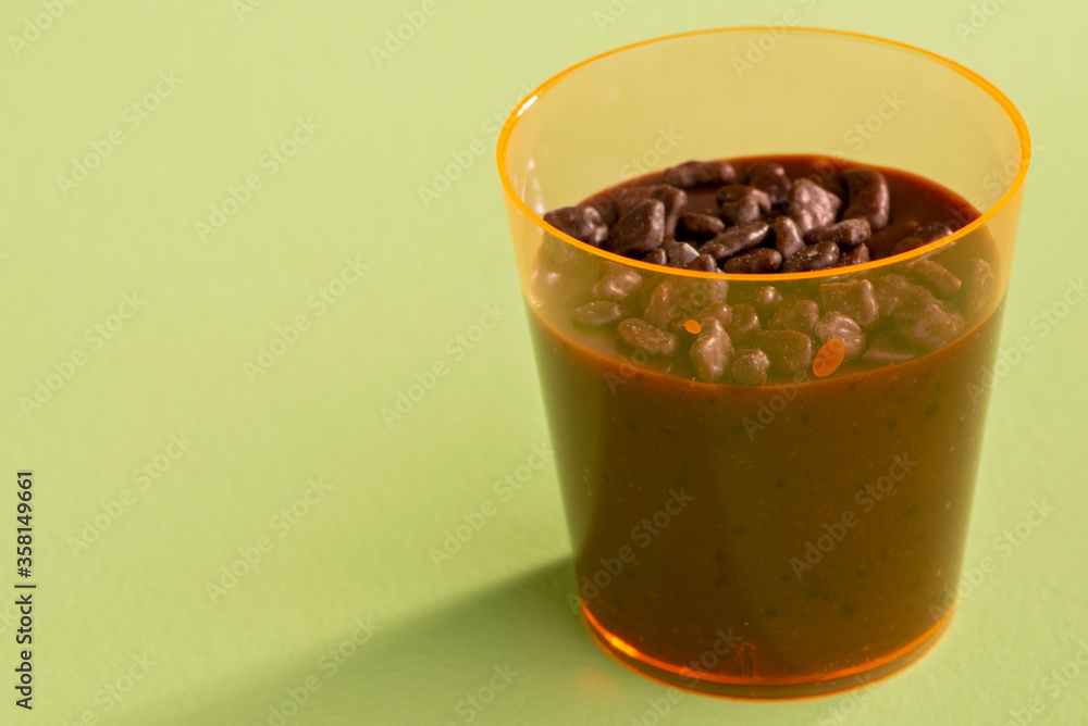 acrylic cup with brigadeiro and chocolate sprinkles on green background acrylic cup with brigadeiro and chocolate sprinkles on green background