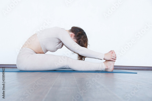 Beautiful girl practices kundalini yoga indoors in daylight.