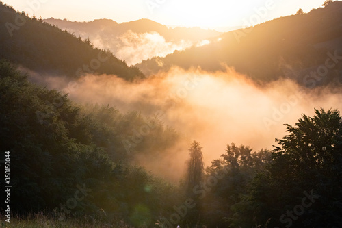 epic summer panorama of foggy sunset in mountains