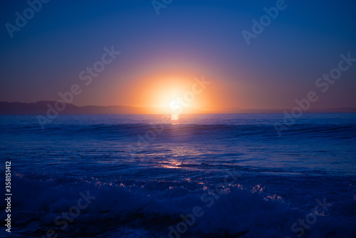Sunset over ocean with waves crashing into shore © rushay