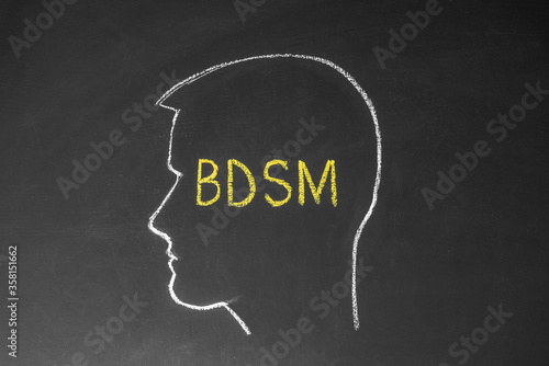Concept man thinks about BDSM. Male head and the inscription BDSM on the chalk board. photo