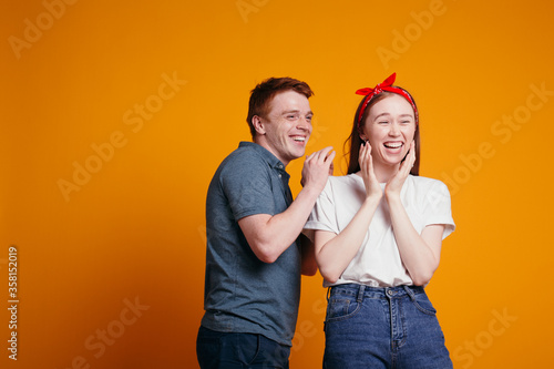 Wallpaper Mural Red-haired guy and girl laughing while shooting in the studio on an orange background. Torontodigital.ca