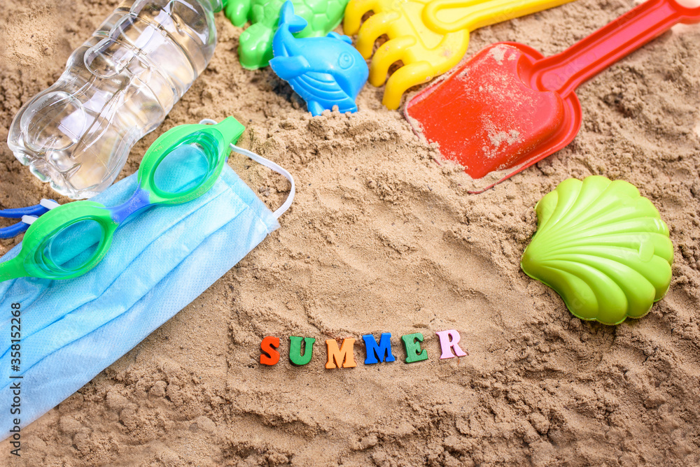 Beach sand with toys for the baby, water, the word summer in colored letters. Beach sand with toys for the baby, water, the word summer in colored letters.