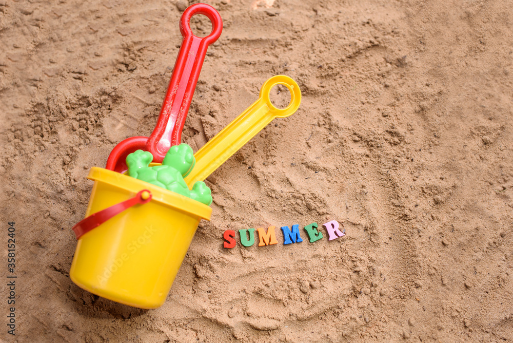 Beach sand with toys for the baby, water, the word summer in colored letters. Beach sand with toys for the baby, water, the word summer in colored letters.