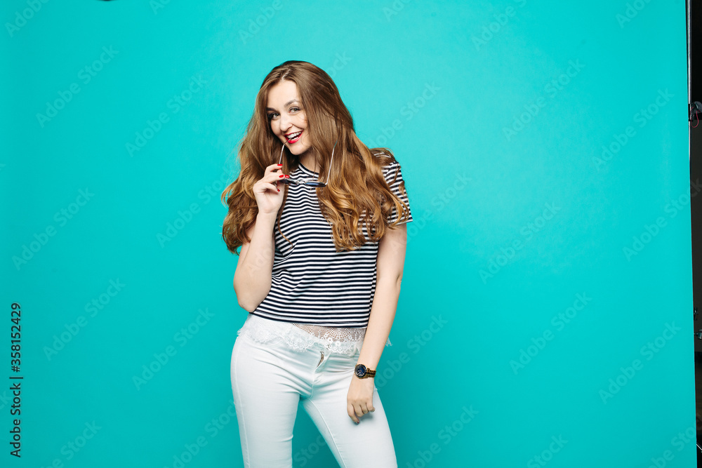 Swag and fashionable girl in sunglasses wearing in striped blouse and white jeans, holding hand on waist and seductive posing.Stylish trendy beautiful woman with perfect haircut, red lips after salon. Swag and fashionable girl in sunglasses wearing in striped blouse and white jeans, holding hand on waist and seductive posing.Stylish trendy beautiful woman with perfect haircut, red lips after salon.