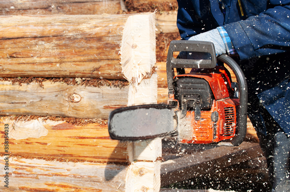 man saws log for home with a chainsaw