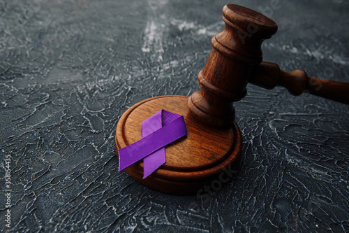 Violet ribbon and gavel on grey background - Concept of Domestic Violence law. photo