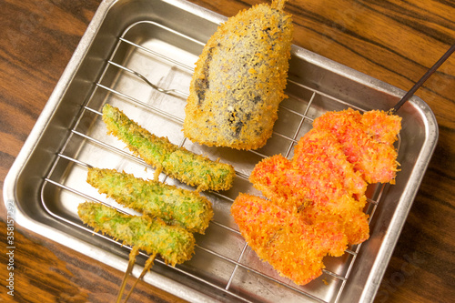アルミニウム製のバットに乗った、なすびと緑のししとうがらし、紅生姜の大阪名物串カツ。Osaka specialty deep-fried skewered meat and vegetables, eggplant,sweet green pepper,red ginger on the plate made by aluminum.