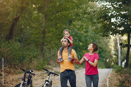 Family in a park. People with a bicycle. Parents with little daughter.