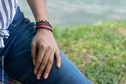 woman's hand with bracelets on jean pants © Juan