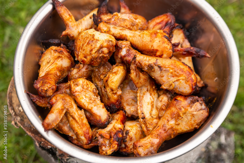 Appetizing grilled chicken legs and wings in a bowl. Close-up. Appetizing grilled chicken legs and wings in a bowl. Close-up.