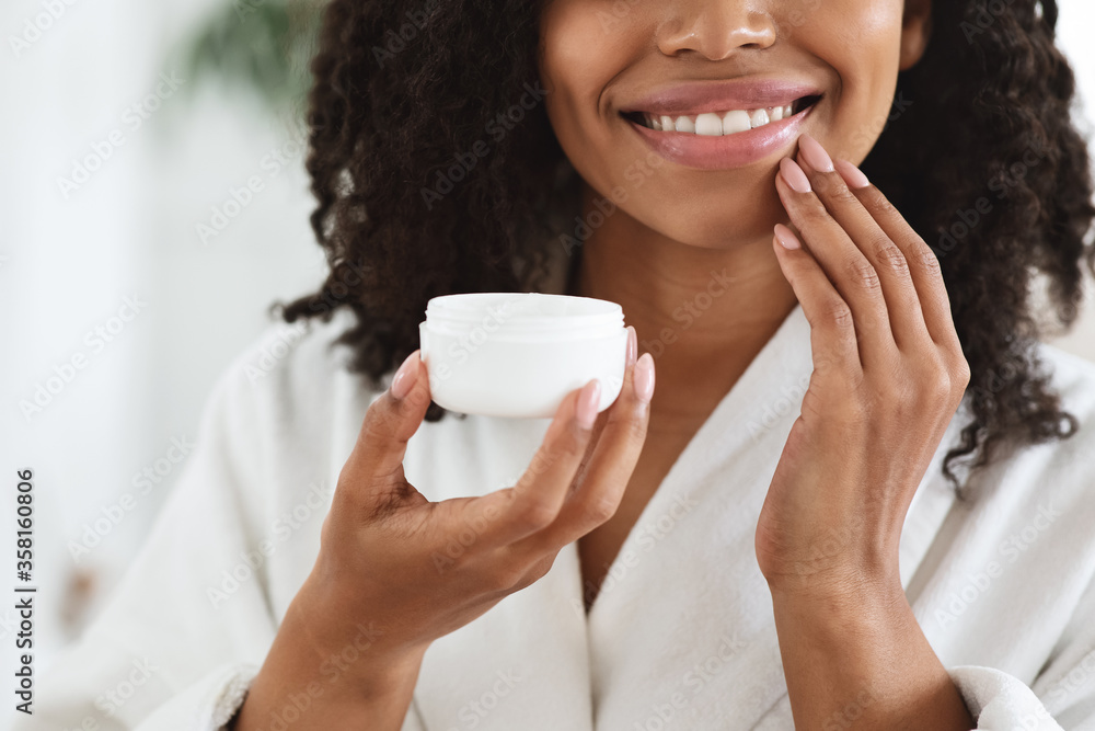 Skin Nutrition. Young afro woman applying moisturizer on her face, closeup Skin Nutrition. Young afro woman applying moisturizer on her face, closeup