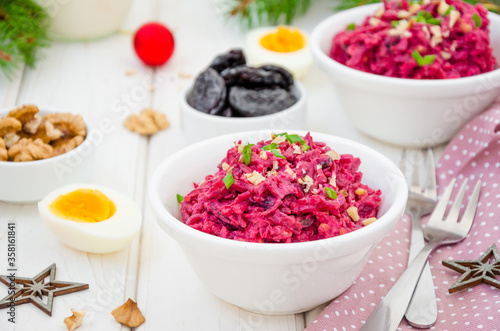 Salad of boiled beet. Beetroot salad with prunes, walnuts, eggs and sour cream in a bowl on white background. Healthy food. Salad for Christmas and New Year. Horizontal orientation. Close up