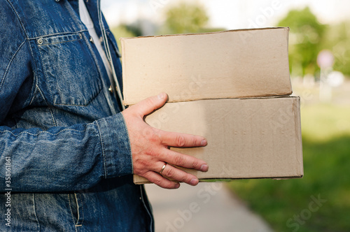 Courier in a face mask with a box in his hands. Portrait from the waist up. Delivery man concept.. Outdoor. photo