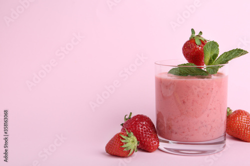 Tasty strawberry smoothie with mint in glass on pink background. Space for text
