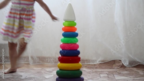 The girl in the room runs around a high pyramid of rings. Rings of different colors photo