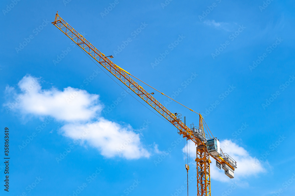 Tower crane. Crane on a background of blue sky with white clouds. Tower crane. Crane on a background of blue sky with white clouds.