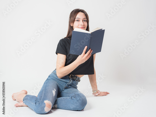 Junges hübsches Mädchen liest am Boden hockend ein Buch photo