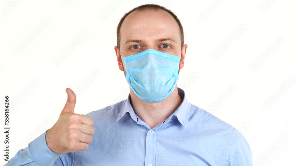 Handsome european man in protective mask holding thumb up. Portrait of confident guy in shirt Handsome european man in protective mask holding thumb up. Portrait of confident guy in shirt