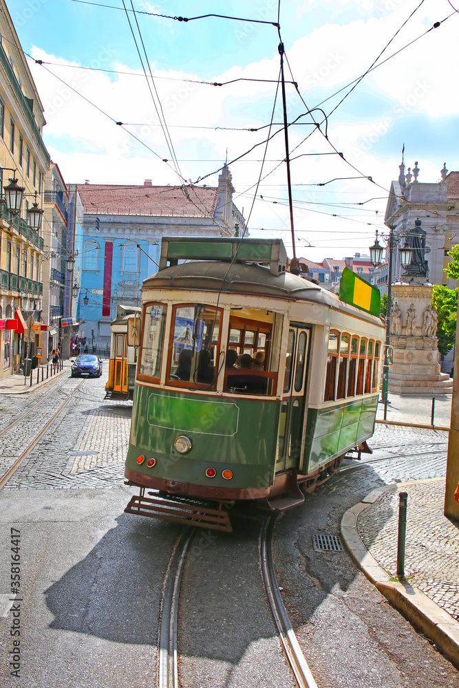 Fototapeta premium Historic green tram against old town streets, part of the tramway network since 1873, Lisbon, capital city of Portugal.