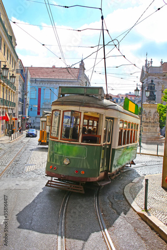 Historic green tram against old town streets, part of the tramway network since 1873, Lisbon, capital city of Portugal.