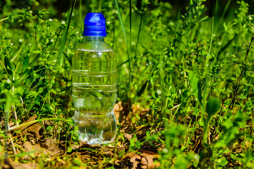 Plastic bottle with the clear water in green grass