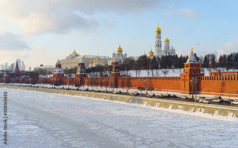 Cars on the Kremlin embankment and the frozen Moscow river on a clear winter day.
