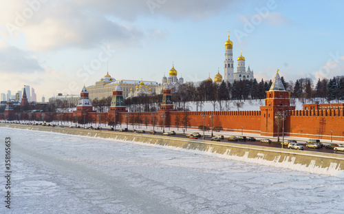 Cars on the Kremlin embankment and the frozen Moscow river on a clear winter day.