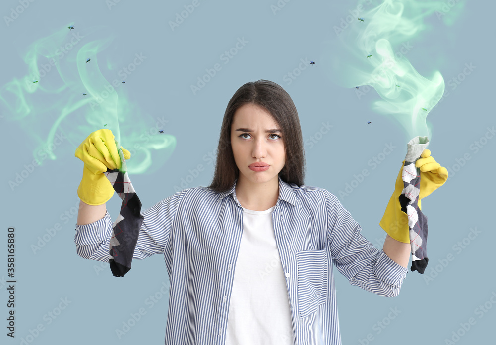 Ταπετσαρία Displeased young woman with dirty stinky socks on color background