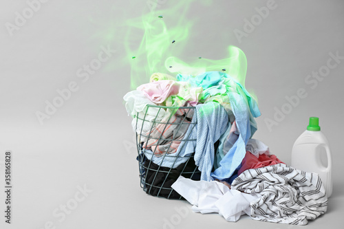 Laundry basket with dirty clothes on grey background