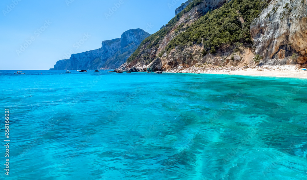 Sardinia, holidays, White sand beach, sea with crystal clear azure water, mountains in the background. Italy, the best beaches in Sardinia.