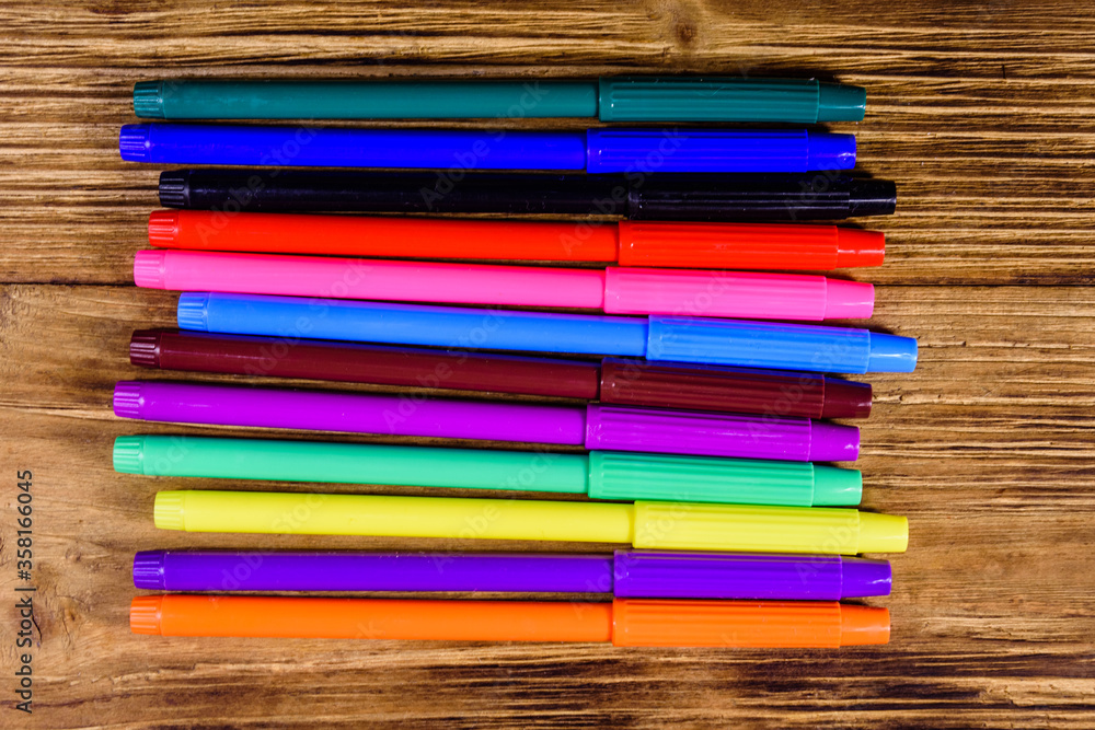 Fototapeta premium Multi colored felt tip pens on wooden table. Top view