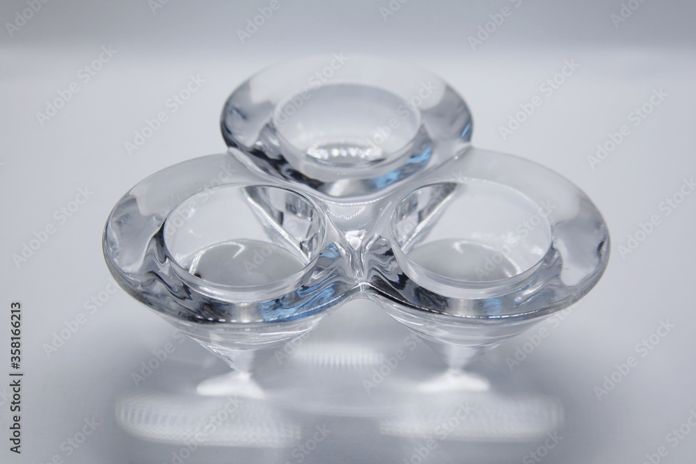 A transparent glass candlestick with a support base and the top of which has three nozzles where the candles are placed to light. A transparent glass candlestick with a support base and the top of which has three nozzles where the candles are placed to light.