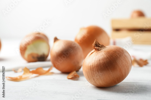 Ripe yellow onion bulbs on white wooden table  closeup