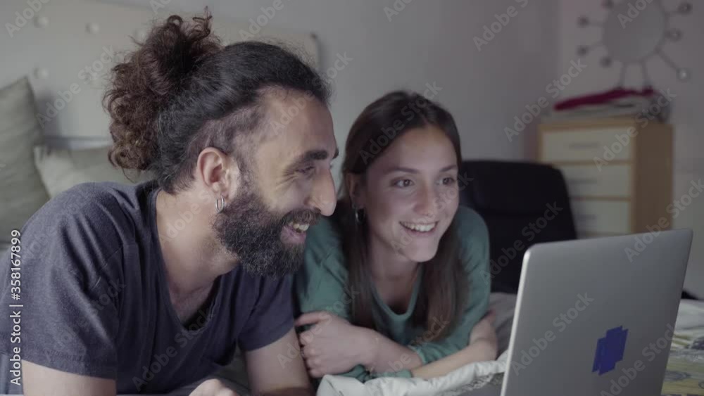 Couple lying on bed and using laptop Couple lying on bed and using laptop