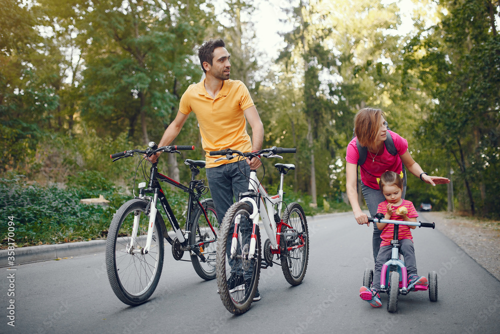 Fototapeta premium Family in a park. People with a bicycle. Parents with little daughter.