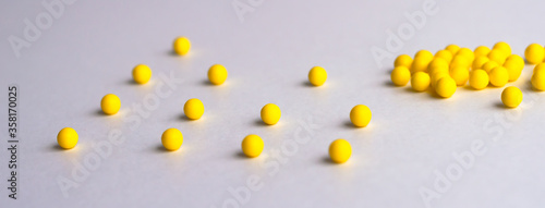 Keep your distance. Round yellow tablets are scattered at a distance on a white glossy table on top. Concept. A place for labels.