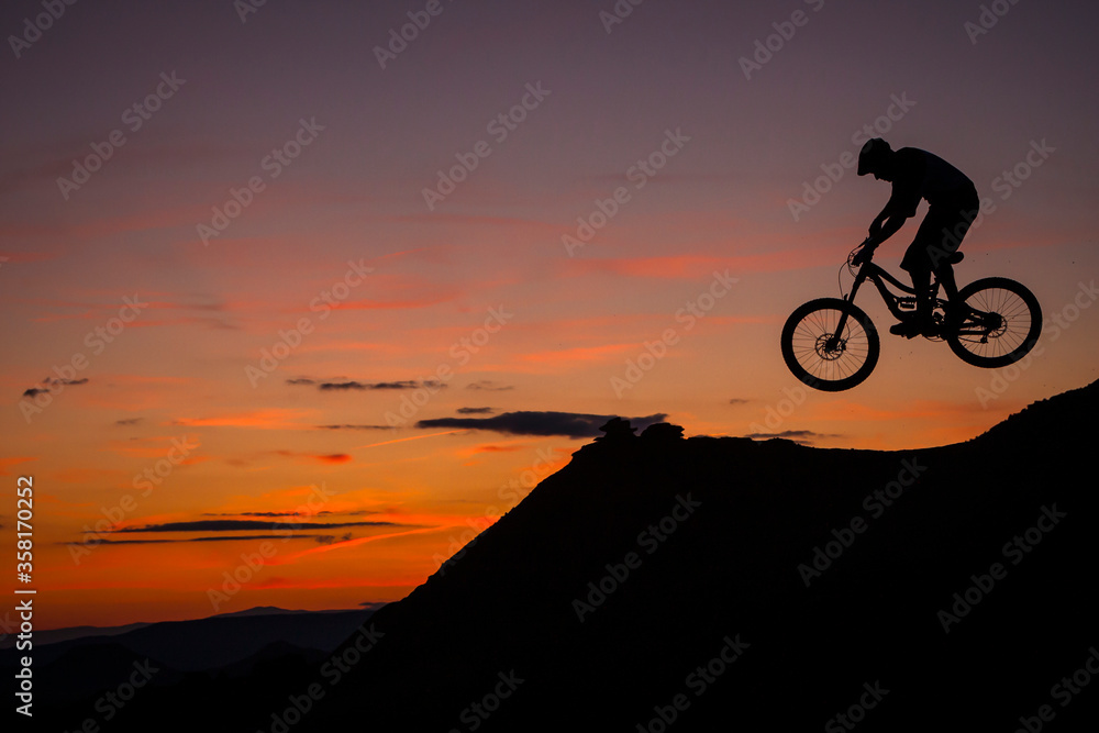 BARDENAS, SPAIN. A mountain biker jumping against sunset sky in the Spanish desert BARDENAS, SPAIN. A mountain biker jumping against sunset sky in the Spanish desert