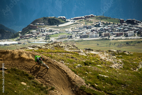 ALPE D'HUEZ, FRANCE. A mountain biker leaves a dust trail behind as he rides a corner on a bike park trail, high above the ski resort of Alpe d'Huez.