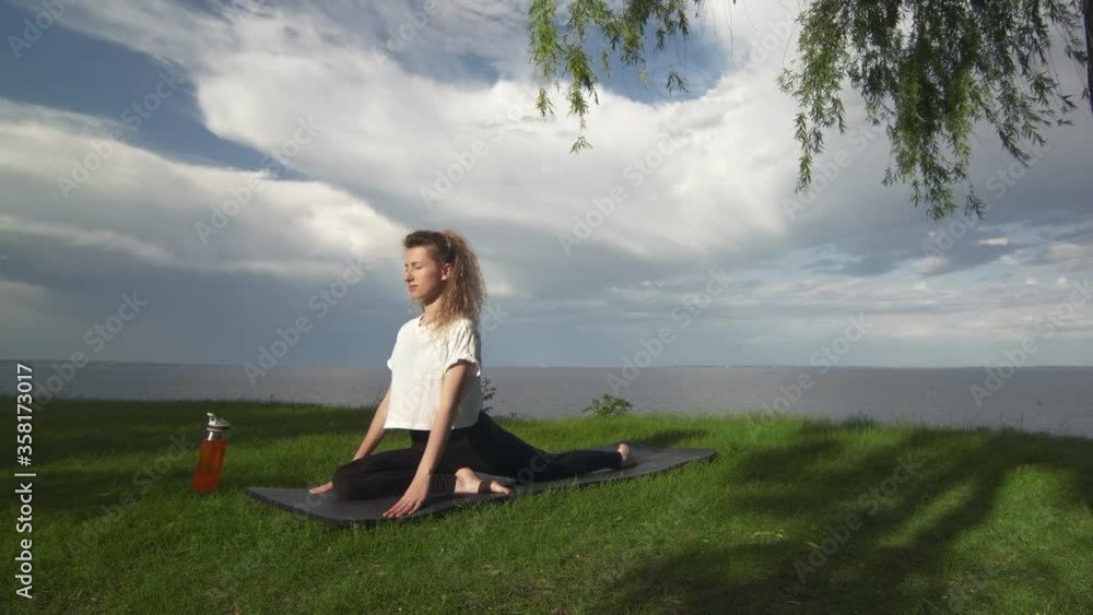 Young fit woman practice yoga on coast near the lake or sea. Woman doing Half Pigeon Pose Young fit woman practice yoga on coast near the lake or sea. Woman doing Half Pigeon Pose