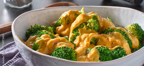Foto steamed broccoli with melted cheddar cheese sauce in bowl