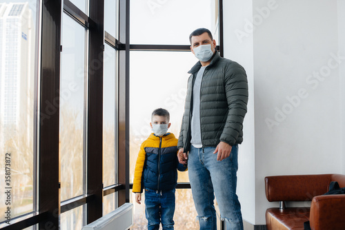 A father with his child stands in a mask during the quarantine. Pandemic, coronavirus
