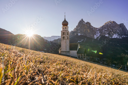 Panoramic view of a mountain scenery in the Dolomites with St. Valentin Church and famous Mount Sciliar in beautiful morning light at sunrise, village of Seis am Schlern, South Tyrol, Italy photo