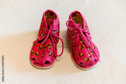 Baby red slippers with a teddy bear motif.